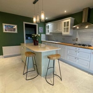 Kitchen cabinets painted white and green island with dark green accent wall