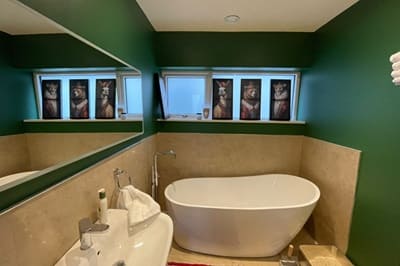 Bathroom after renovation with green walls and white bath