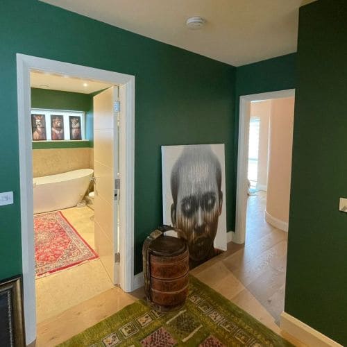 Hallway with dark green walls featuring white doors and architraves