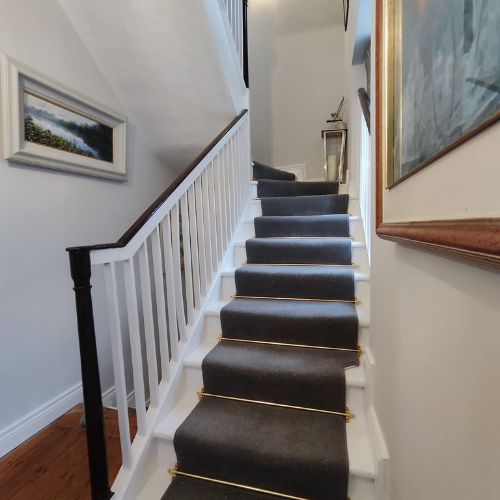 Staircase with white banister and brown handrail with brown runner